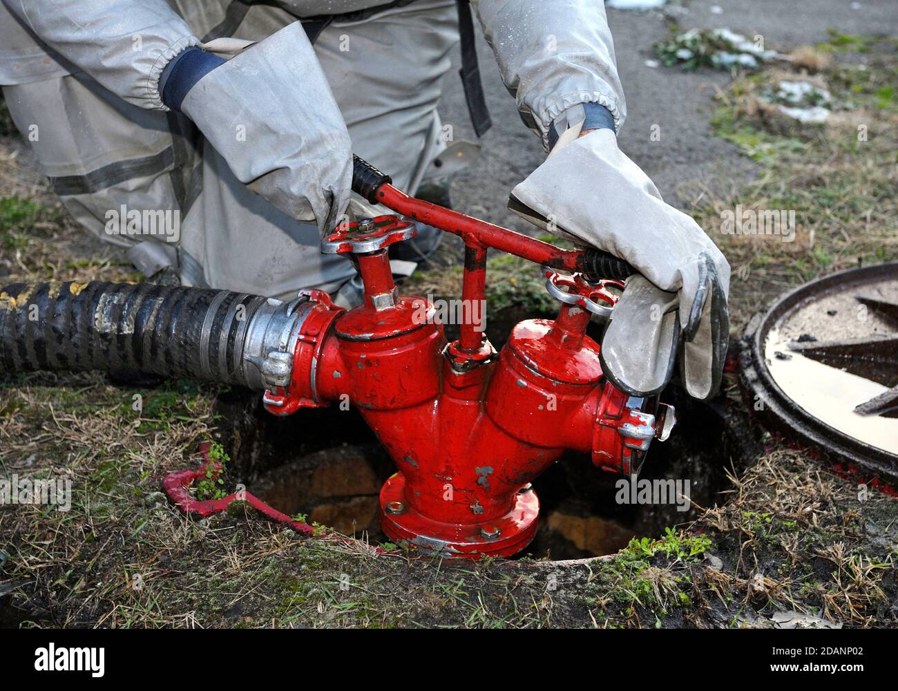 Mani di soccorso in guanti protettivi ruotando una valvola di a. idrante di fuoco al territorio di pianta di acqua Foto Stock
