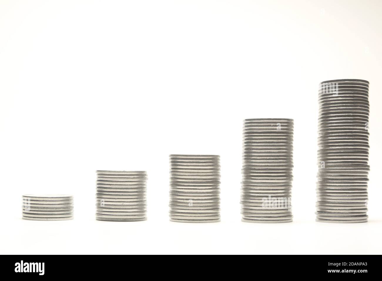 Pile di monete d'argento sotto forma di diagramma, isolate su sfondo bianco. DOF poco profondo. Foto Stock