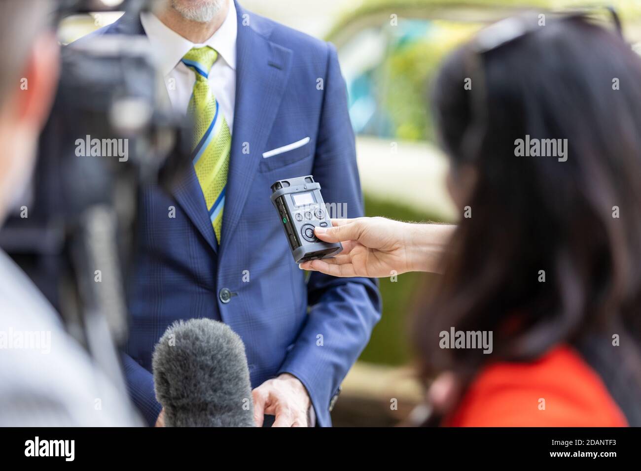 Giornalisti che tengono un registratore digitale e un microfono durante una conferenza stampa o un briefing con la stampa con il business person Foto Stock