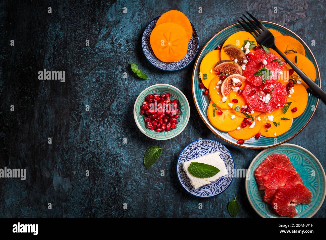 Insalata invernale sana - insalata di carpaccio di Persimmon con melograno, formaggio feta, pompelmo rosa e fichi Foto Stock