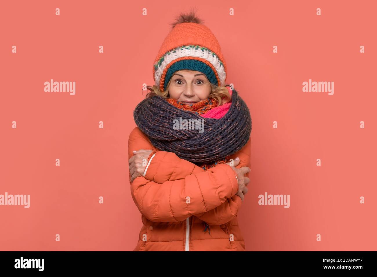 Donna gelida matura che indossa diverse sciarpe e cappelli. Foto Stock