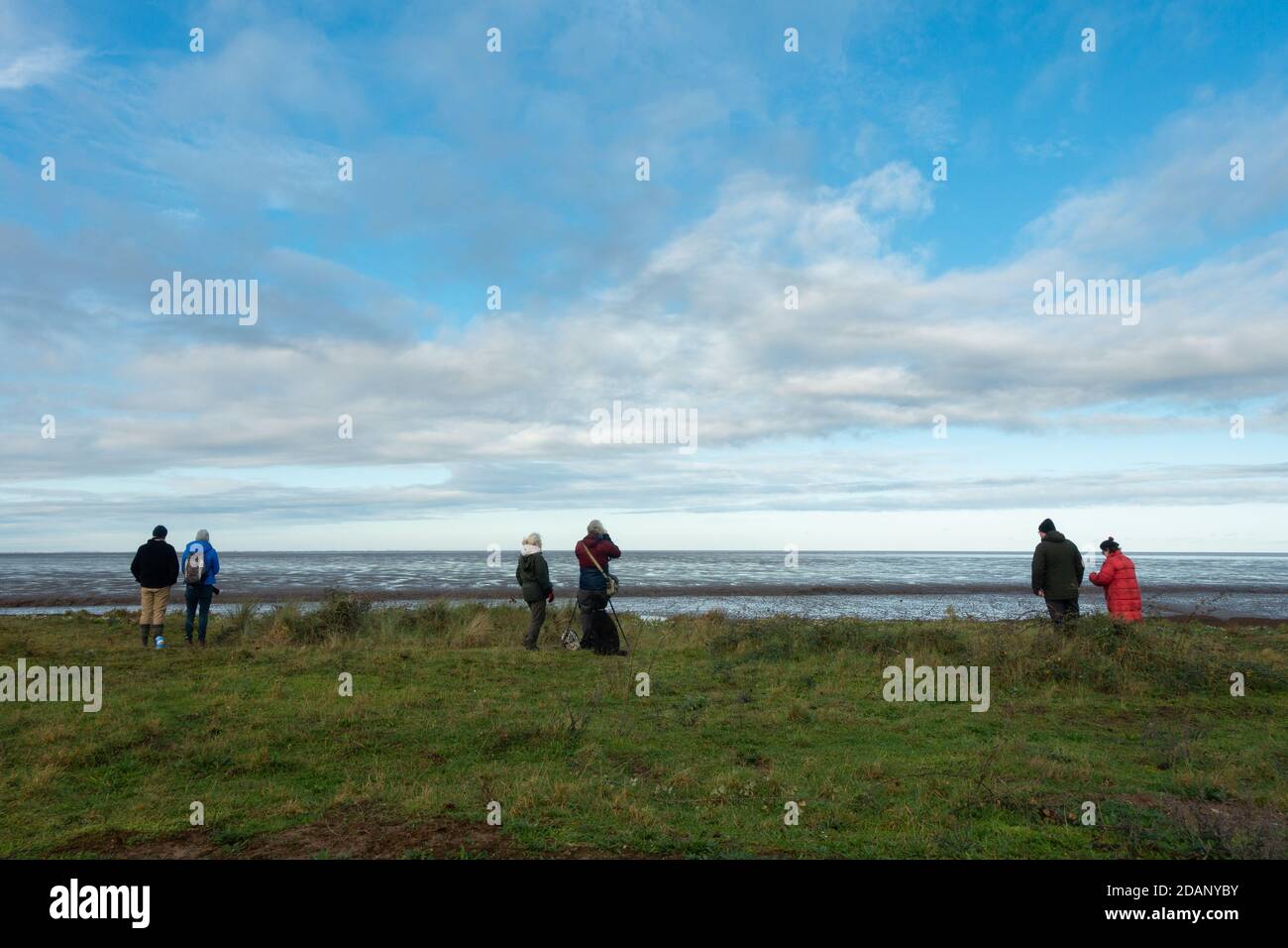 Bird watcher mantenendo la loro distanza l'uno dall'altro in tempi COVID - socialmente distanziando a RSPB Snettisham in attesa del knot murmuration, Norfolk Foto Stock