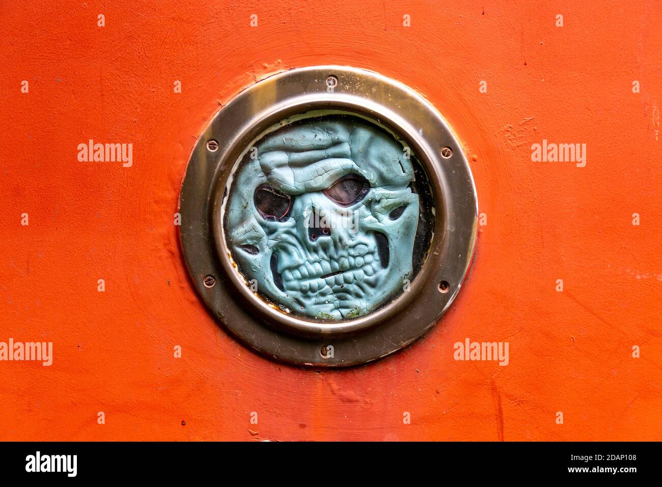 Oblò in una casa galleggiante decorata con una maschera spaventosa lungo Grand Union Canal, Colne Valley, Uxbridge, UK Foto Stock