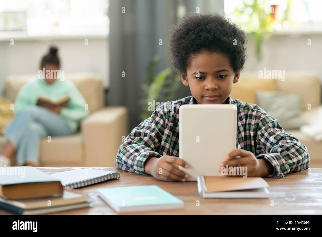 Carino scolaro elementare di etnia africana guardando lezione online a. casa Foto Stock