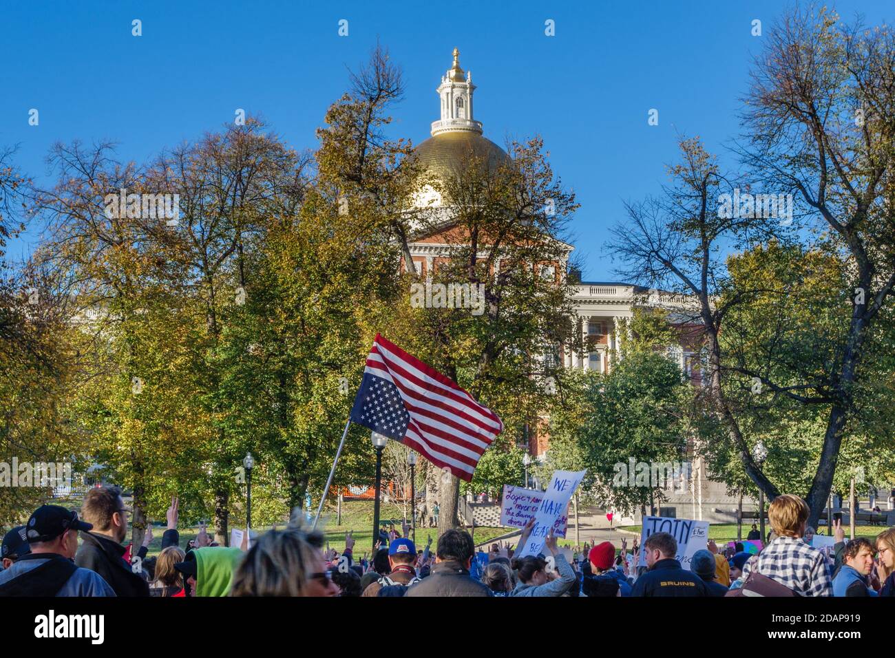 Manifestanti al anti-Trump Love Rally di Boston Common dopo le elezioni presidenziali americane con bandiera statunitense rovesciata. La Massachusetts state House in Foto Stock