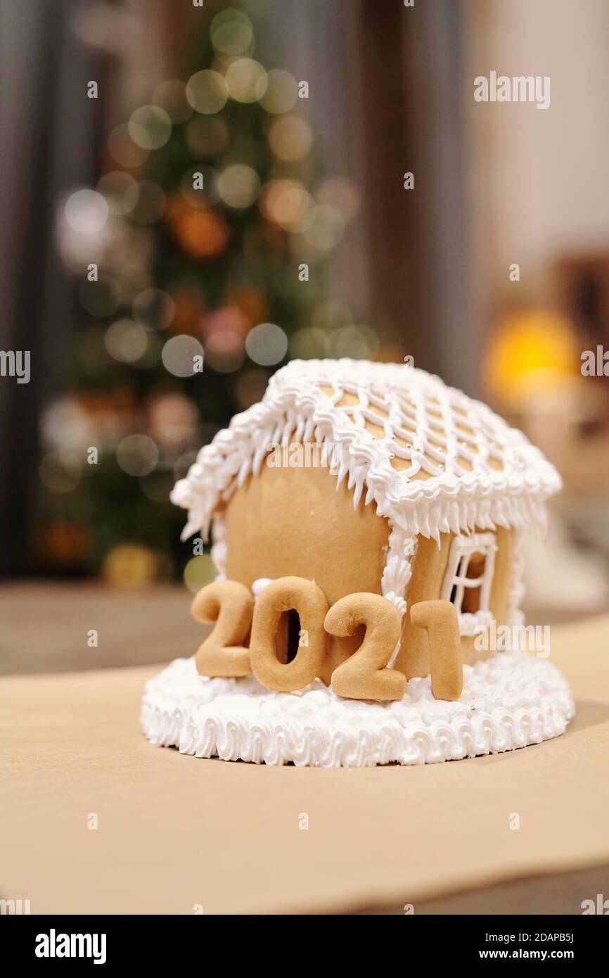 Gustosa casa di pan di zenzero fatta in casa in piedi contro l'albero di Natale frizzante Foto Stock