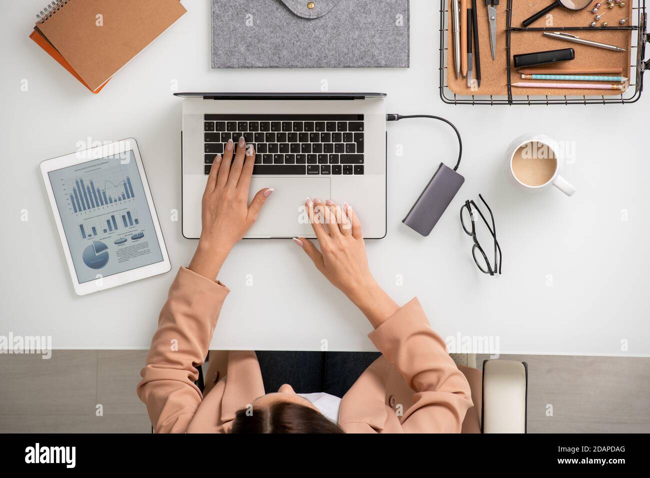 Panoramica di una giovane ed elegante donna d'affari seduta davanti alla scrivania di computer portatile Foto Stock