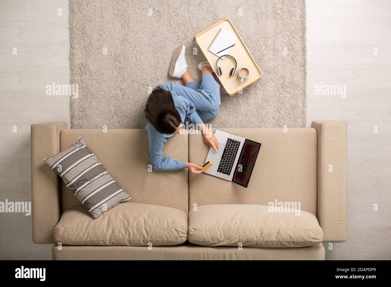 Giovane donna riposante che va a pagare con la carta durante l'acquisto merci nel negozio online Foto Stock