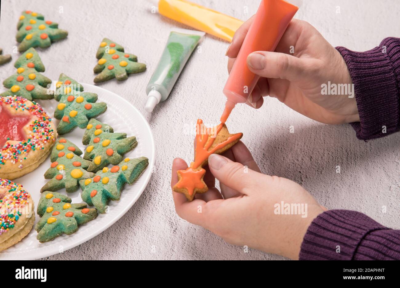 Le mani delle donne sono decorate con glassare le torte di Natale. Preparazione per la celebrazione del Natale e del Capodanno. Orientamento orizzontale. Foto Stock