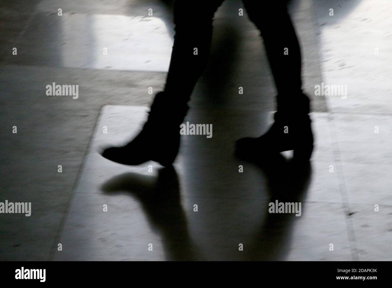 Silhouette scure delle gambe di quattro che camminano sul fianco in luminosa retroilluminazione, Italia Milano Foto Stock