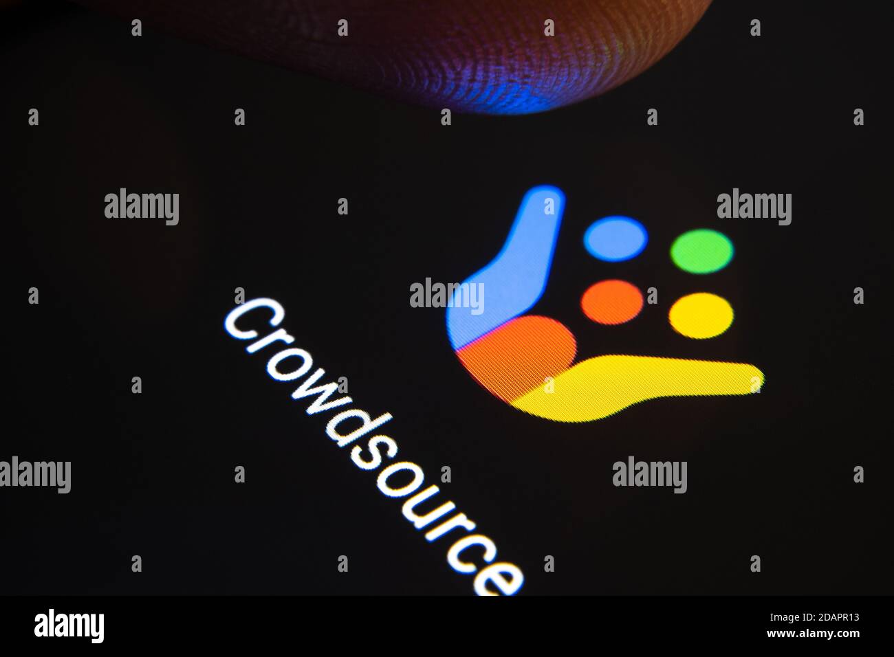 Stafford / Regno Unito - Novembre 12 2020: Google Crowdsource app e sfocato dito punta sopra di esso pronto a premere lo schermo dello smartphone. Foto Stock