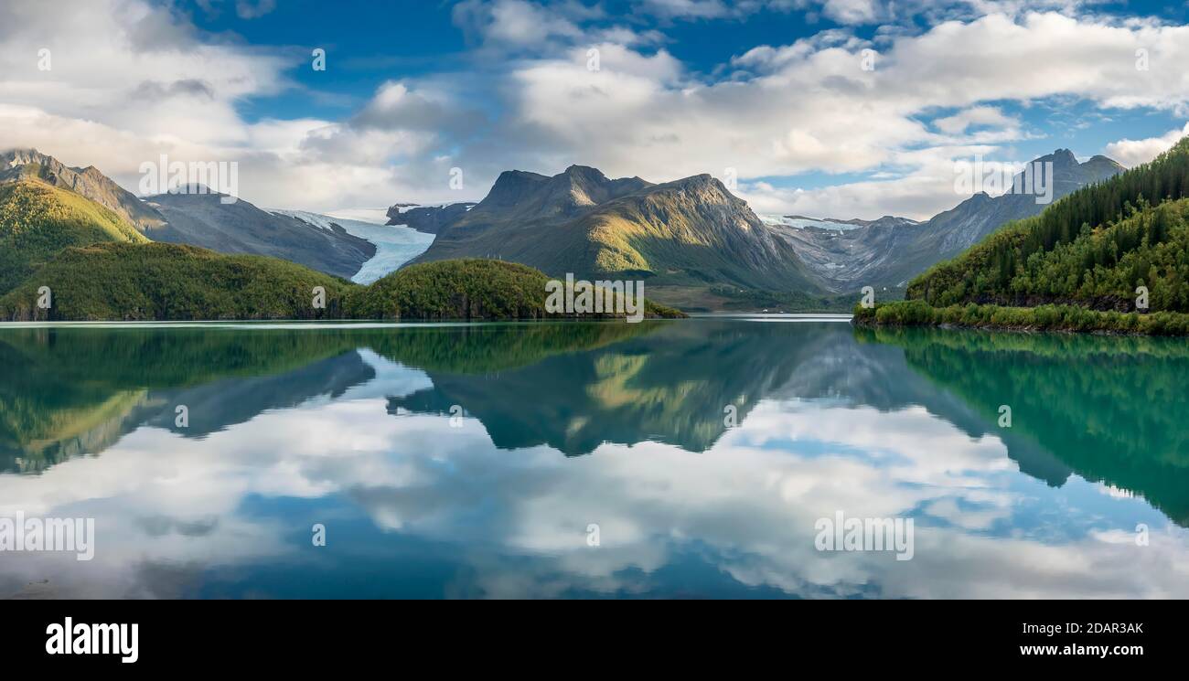 Ghiacciaio di Svartison con lingua glaciale, catena montuosa boschiva riflessa in fiordo calmo, Meloy, Nordland, Norvegia Foto Stock