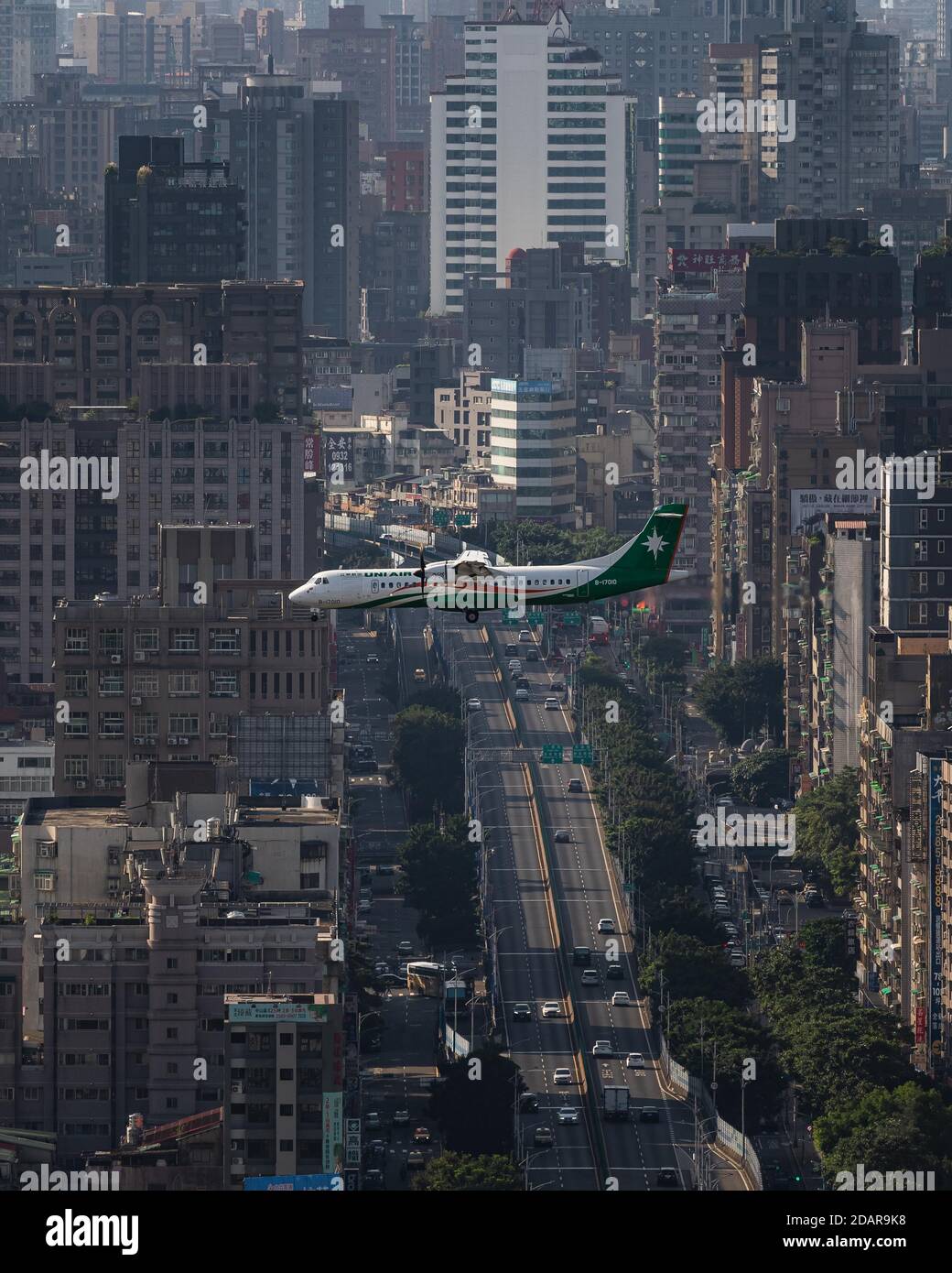 L'aereo UNI Air vola sull'area urbana con strade e grattacieli, Taipei, Taiwan Foto Stock