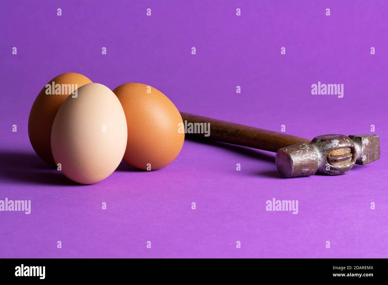 Tre uova di pollo e un martello. È stata costruita una scena che induce ansia. Foto Stock