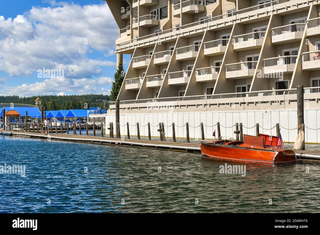 Una barca in legno attracca lungo la passerella vicino alla barca coperta scivola al porto turistico di un hotel sul lago durante l'estate. Foto Stock