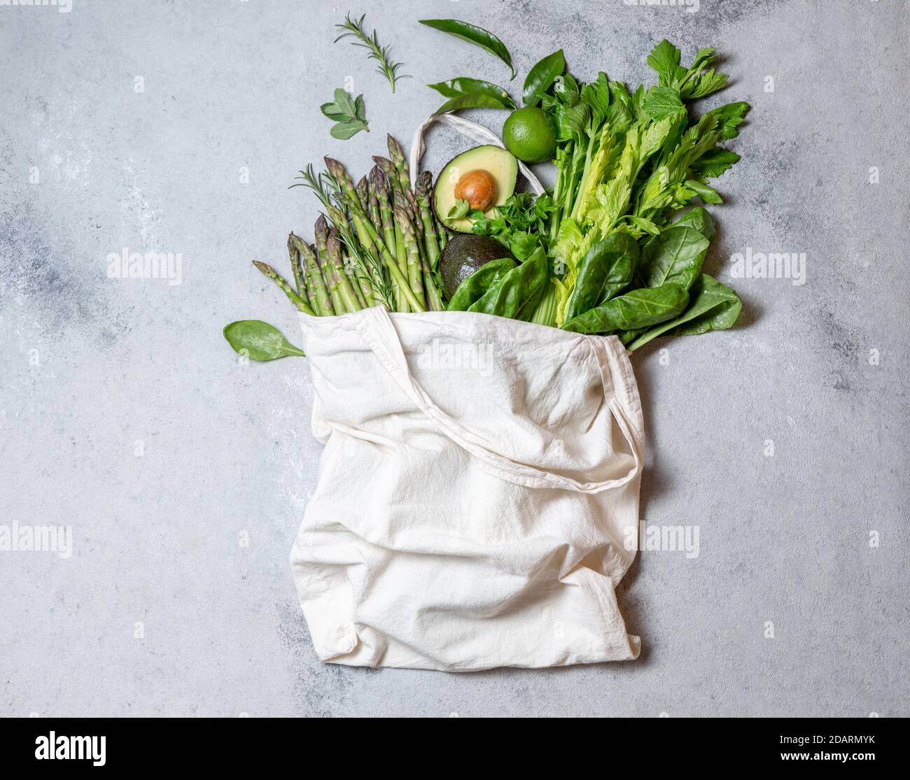 Ingredienti alimentari sani verdure verdi e frutta in sacchetto di lino ecologico, zero rifiuti e concetto di consumo pulito. Sfondo grigio Foto Stock