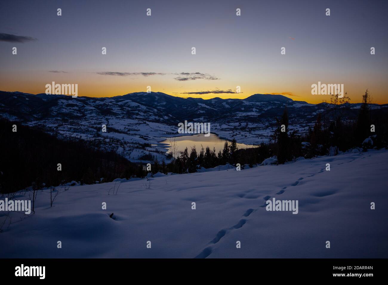 Colorata serata al tramonto sul lago di montagna Rovni nella neve, bella natura scena invernale in Serbia Foto Stock