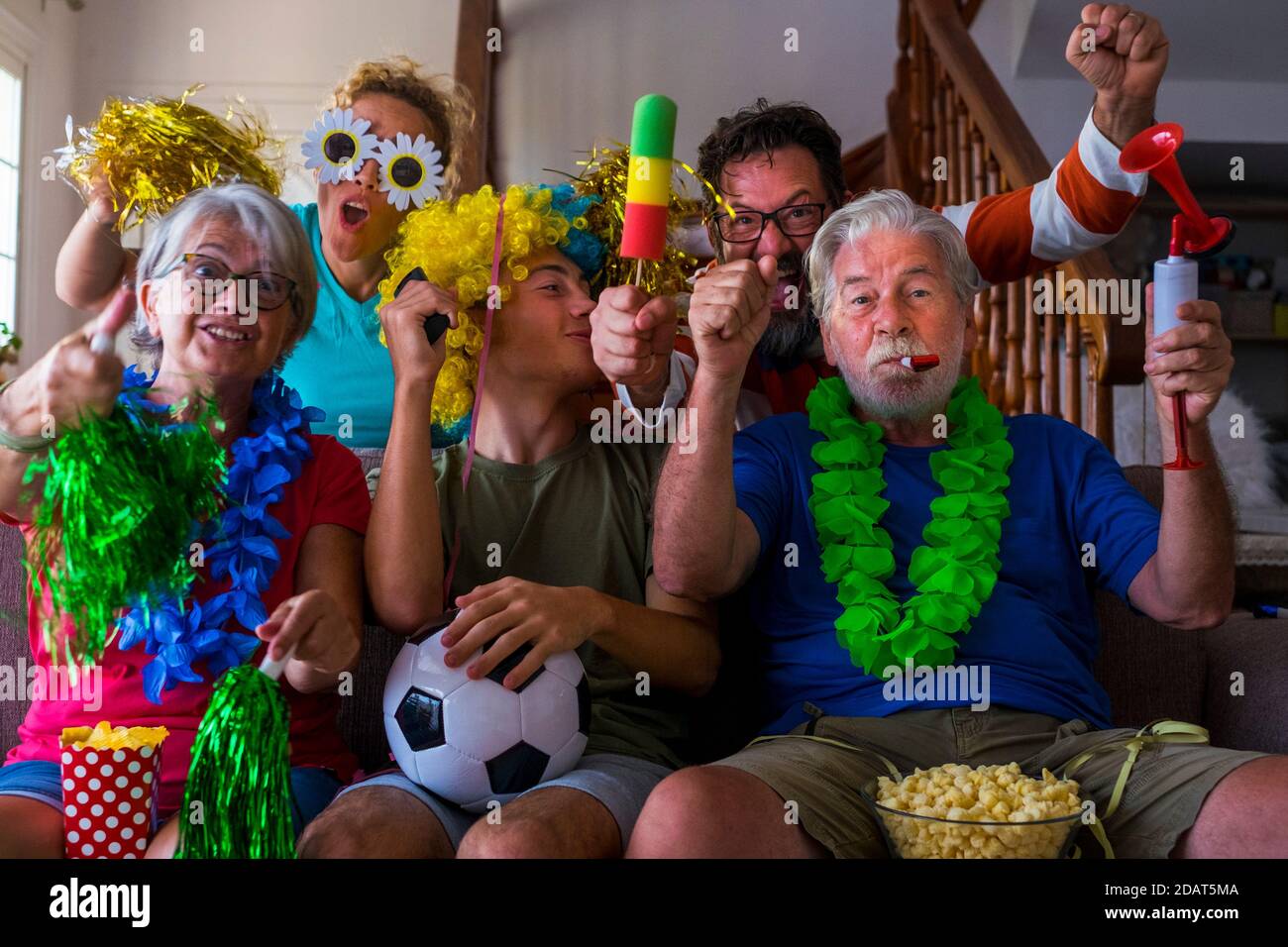 Gruppo di pazzi e colorati sostenitori del calcio festeggiano e esultano durante la partita - età miste della famiglia caucasica e gli amici godono di sport su Foto Stock