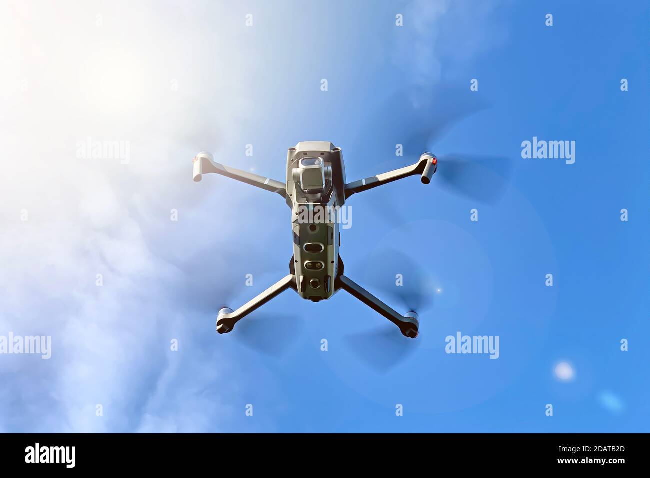 Drone che si inzita su un cielo blu e su uno sfondo di sole, con luci svasate. Vista sottostante con spazio per il testo. Foto Stock Drone che si inzita su un cielo blu e su uno sfondo di sole, con luci svasate. Vista sottostante con spazio per il testo. Foto Stock