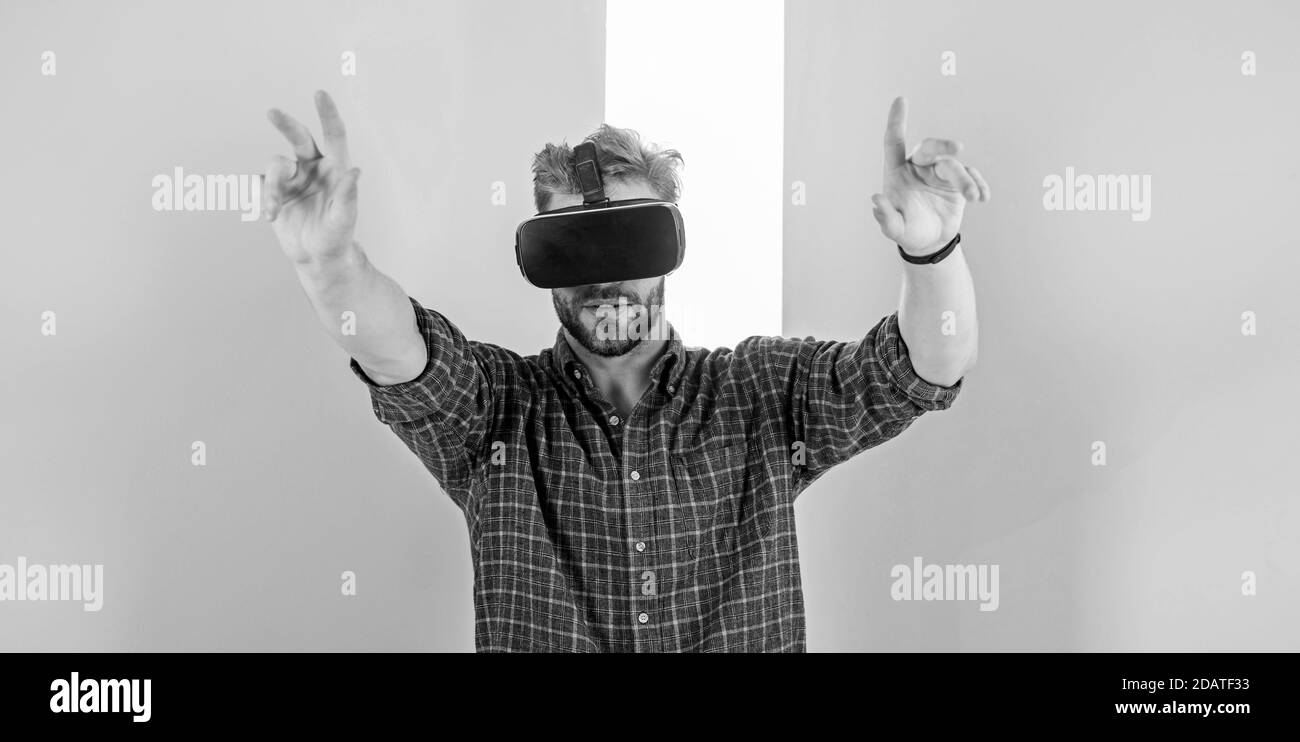 Interazione nella realtà virtuale con la superficie digitale. Uomo unshaven ragazzo con occhiali VR, sfondo rosa. Hipster utilizza tecnologie moderne per l'intrattenimento. Ragazzo con occhiali VR o display montato sulla testa. Foto Stock