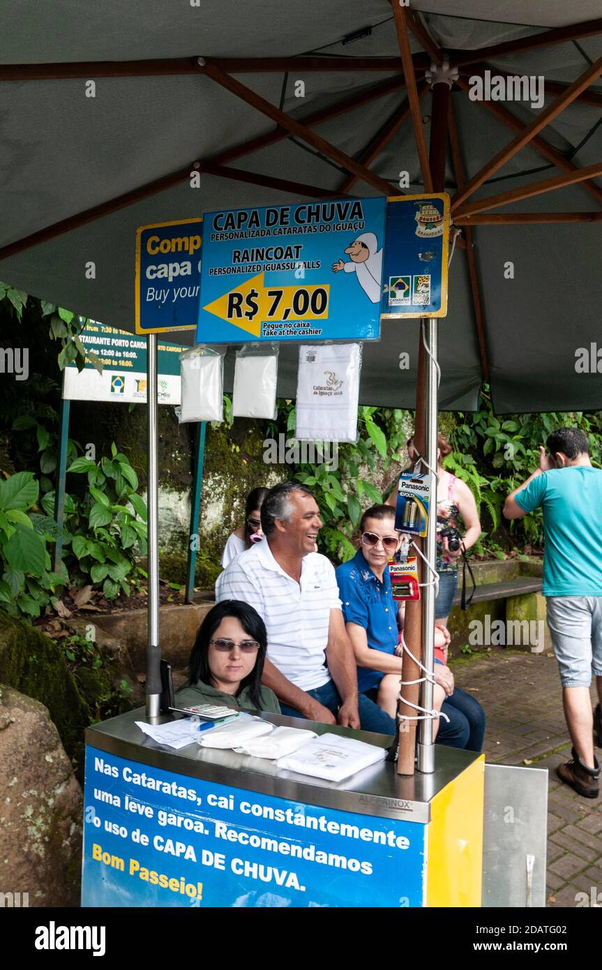 Un assistente di vendita presso una bancarella di impermeabile che vende mac in plastica ai visitatori delle cascate di Iguazu nel Parco Nazionale, Brasile. Le cascate Iguazu i Foto Stock