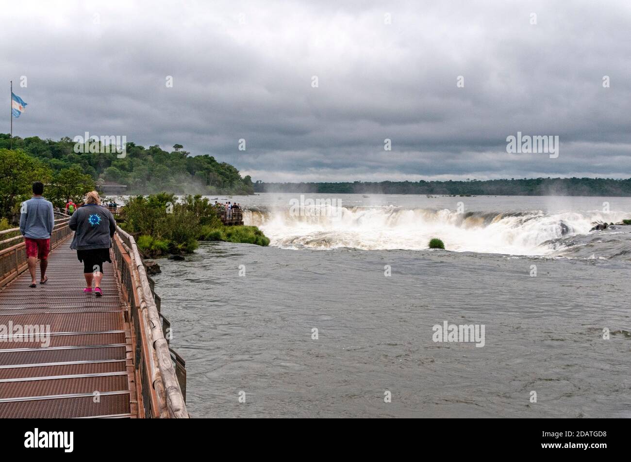 I visitatori si dirigono lungo la passerella costruita a purpos fino alle cascate Devil's Throat, alte 82 metri. È la più grande cascata delle cascate di Iguazu all'interno del Foto Stock