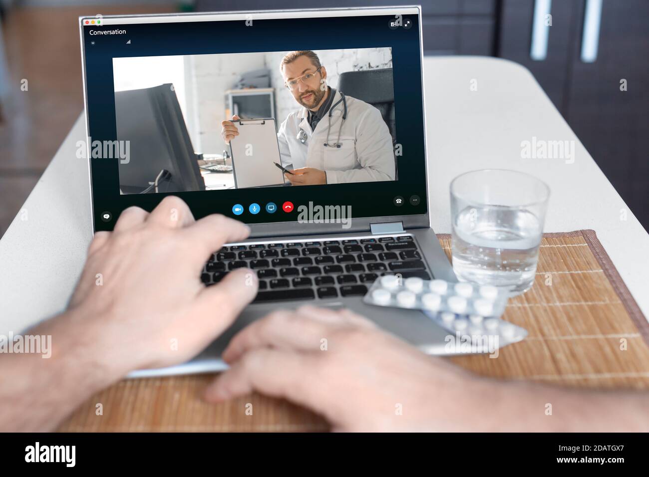 Una vista ravvicinata della mano di un paziente davanti a un computer portatile durante una consultazione online con un medico. Foto Stock