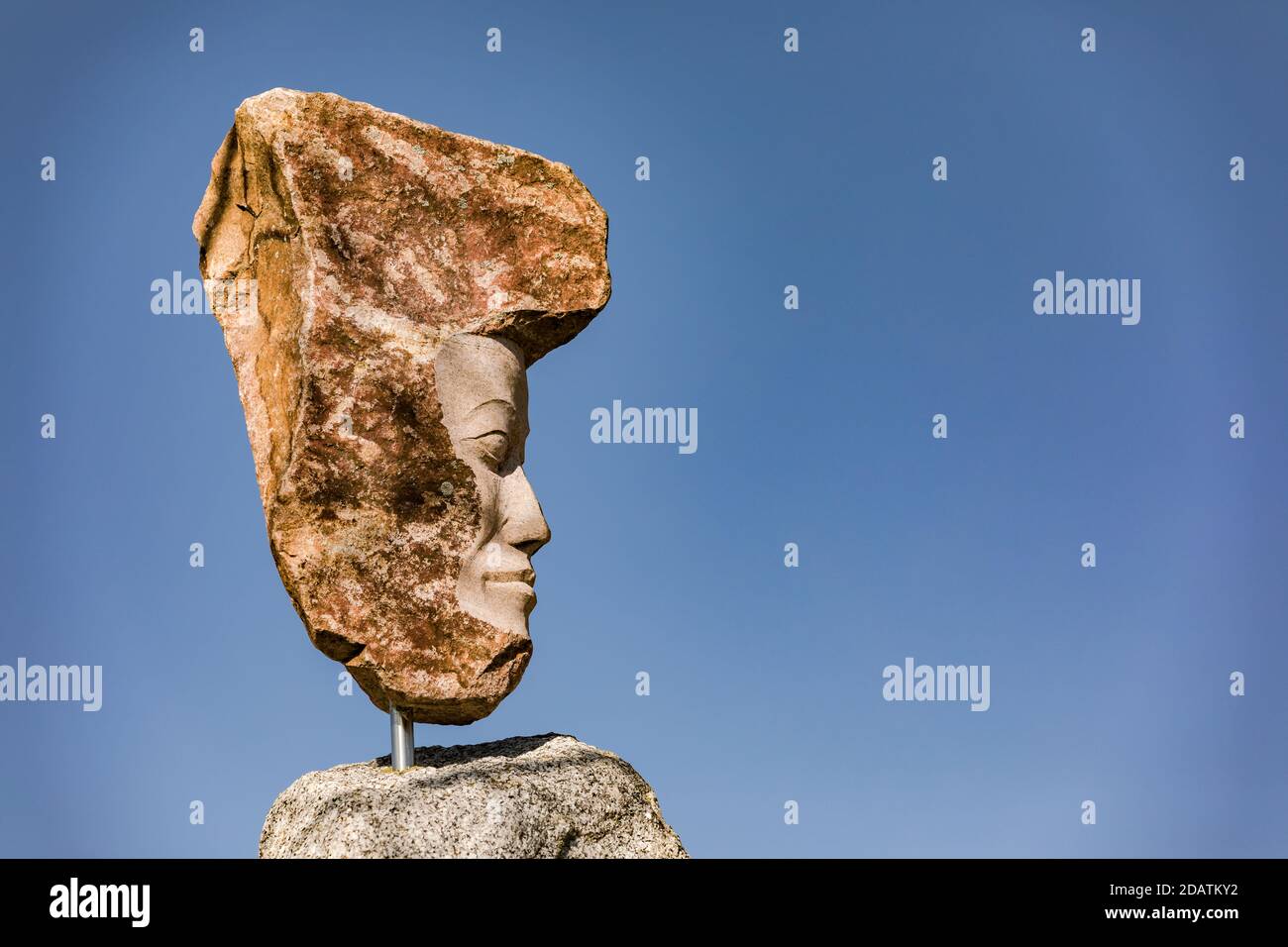 grande statua di granito contro un cielo blu e il sole Foto Stock