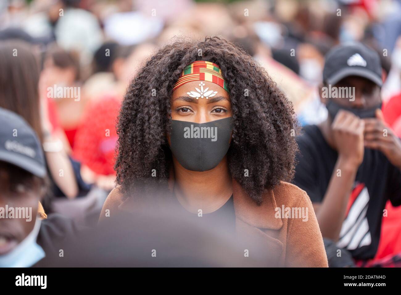 Una giovane donna indossa una maschera facciale, gioielli di faccia e una fascia di testa a una marcia Black Lives Matter di protesta. Foto Stock
