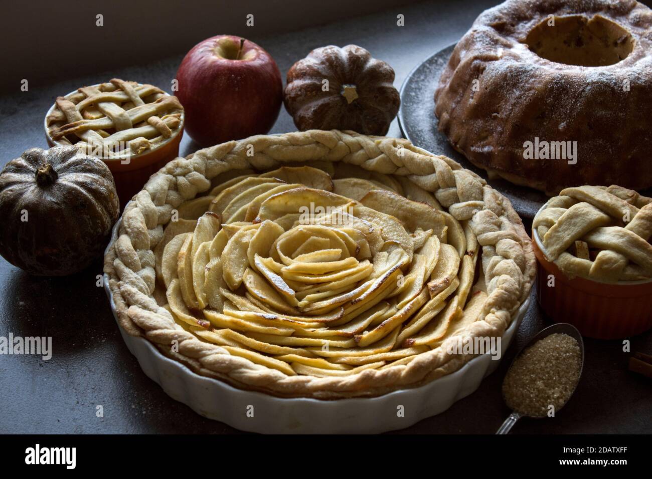 Crostate di dessert su un tavolo. Foto dall'alto di varie torte di mele, torte e crostate, prugne fresche, mele e zucche. Idee menu autunno. Foto Stock