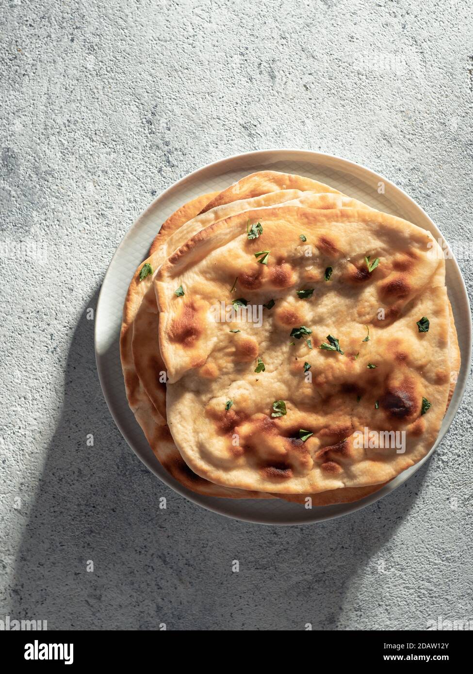 Pane fresco naan su fondo grigio cemento con spazio copia. Vista dall'alto di diversi piatti naan perfetti. Verticale Foto Stock