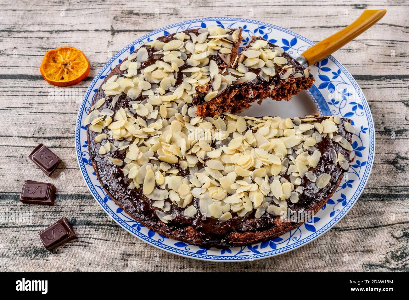 Torta di cacao e cocco ricoperta di glassa al cioccolato e scaglie di mandorle, con una fetta tagliata Foto Stock