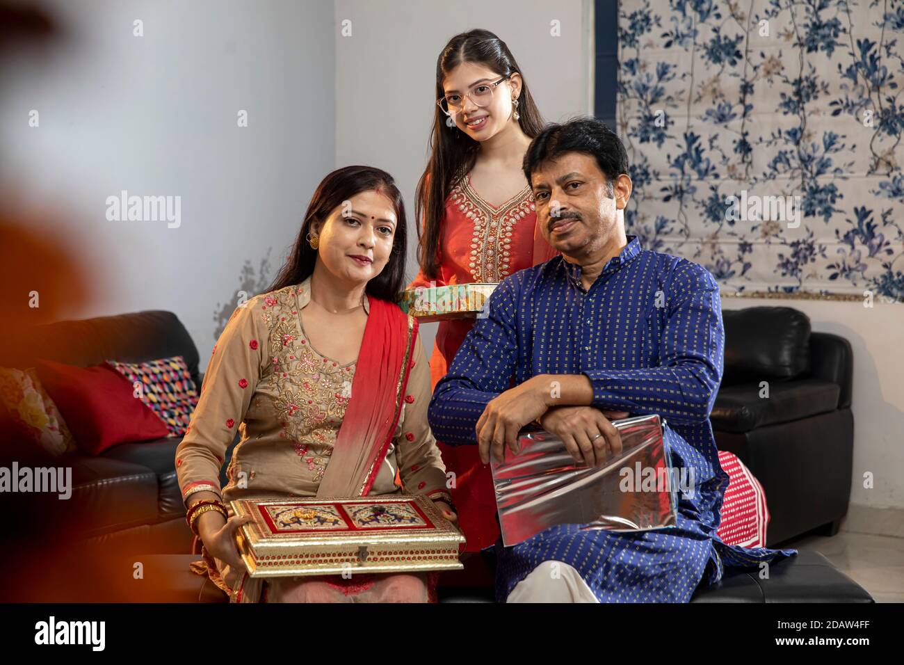 Famiglia indiana che tiene doni in occasione di festival, cultura e tradizioni, Diwali e holi celebrazioni, genitori con bambino. Foto Stock