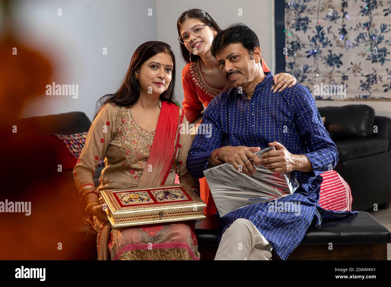 Famiglia indiana che tiene doni in occasione di festival, cultura e tradizioni, Diwali e holi celebrazioni, genitori con bambino. Foto Stock