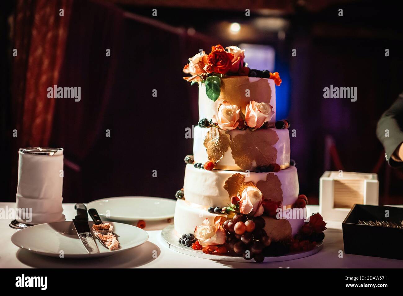 Torta nuziale su quattro livelli sul tavolo in sala scura Foto Stock