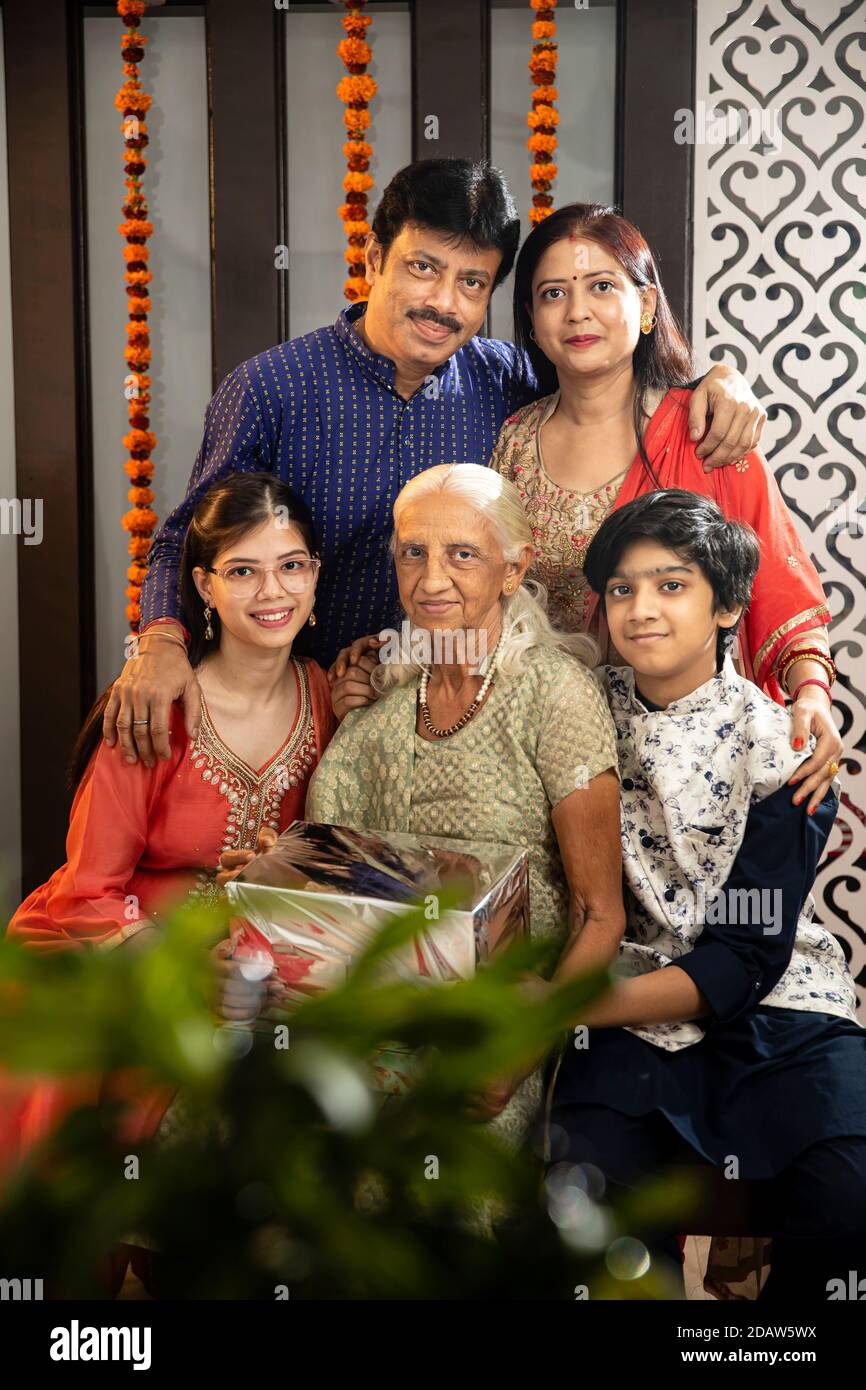 Tre generazioni di una famiglia indiana che si pone insieme, genitori, nonna e bambini. Foto Stock