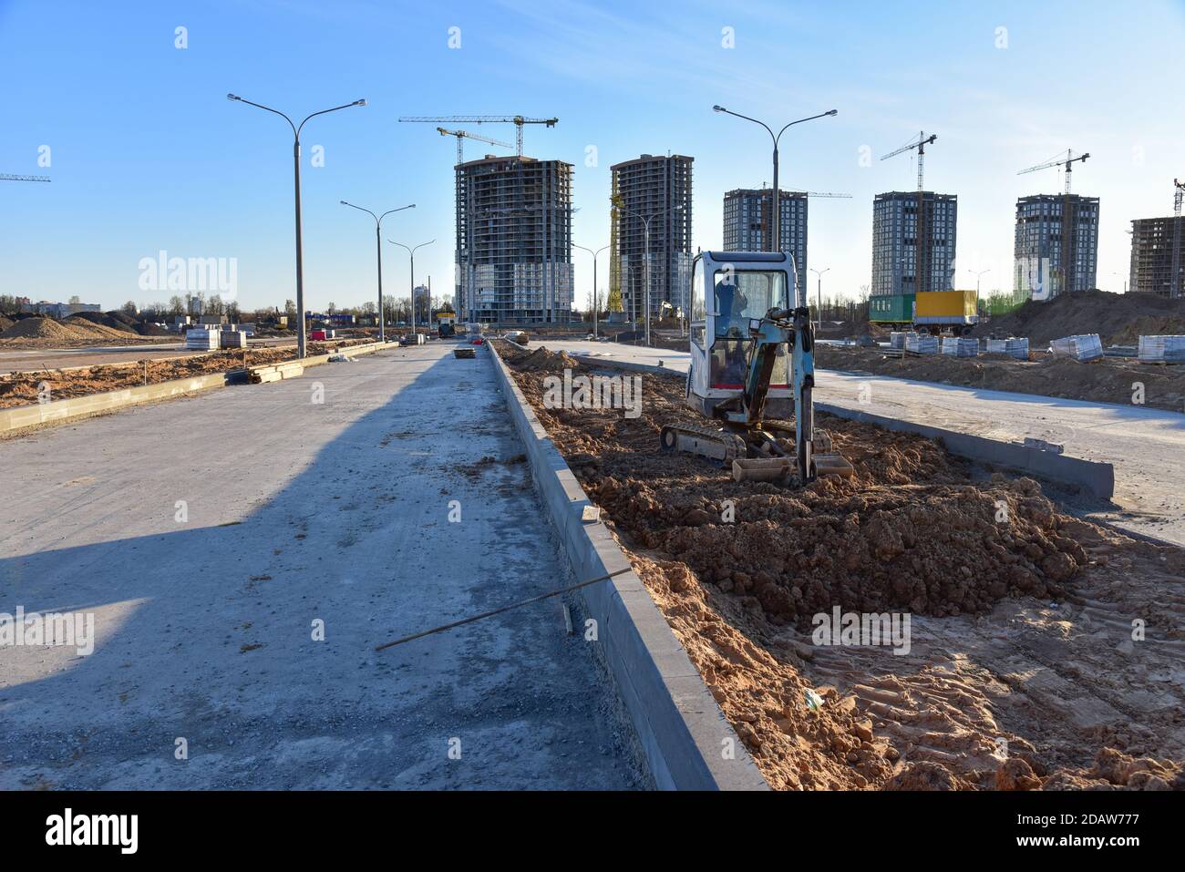 Miniescavatore durante lavori stradali in cantiere. Sabbia per l'installazione di bordi, marciapiedi e blocchi di calcestruzzo sulla strada. posa della pavimentazione sla Foto Stock