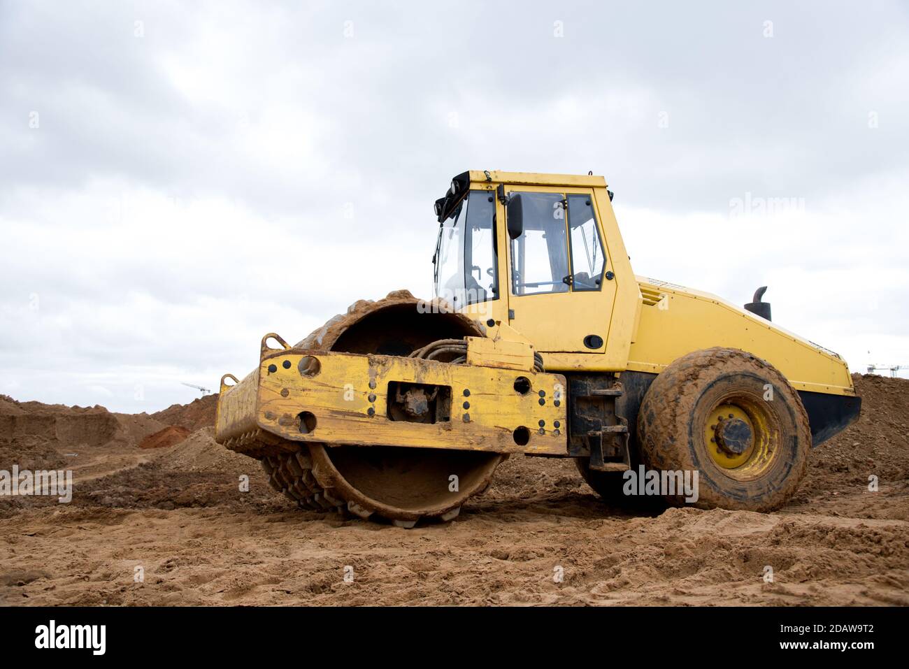 Compattatore per terreno in cantiere. Rullo vibrante monocilindrico per il livellamento di terreno, ghiaia, calcestruzzo o asfalto nella costruzione di strade Foto Stock