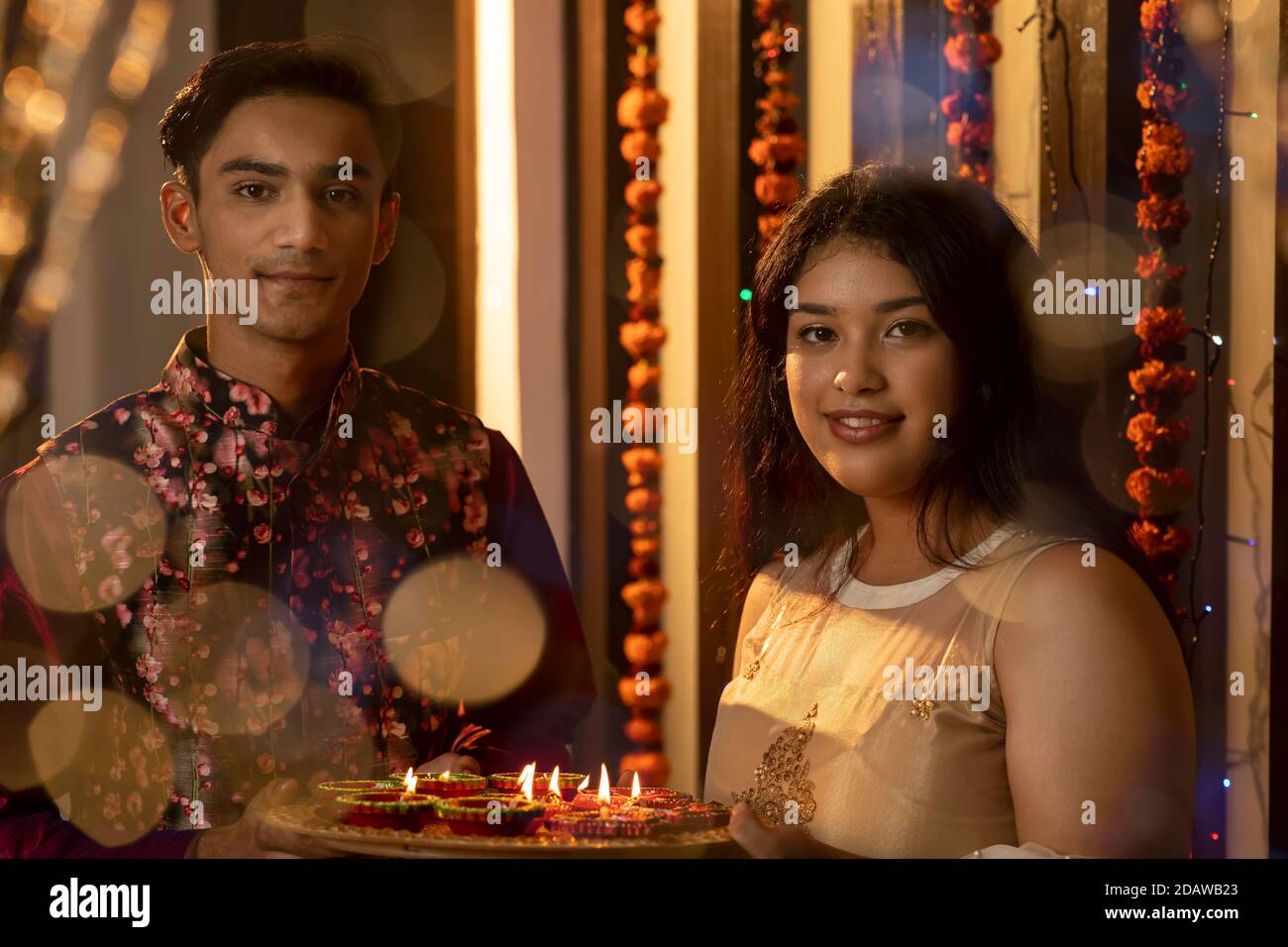Ritratto di un uomo e di una donna indiani che illuminano diya e lampade in occasione delle feste di Diwali. Celebrazioni a casa. Foto Stock