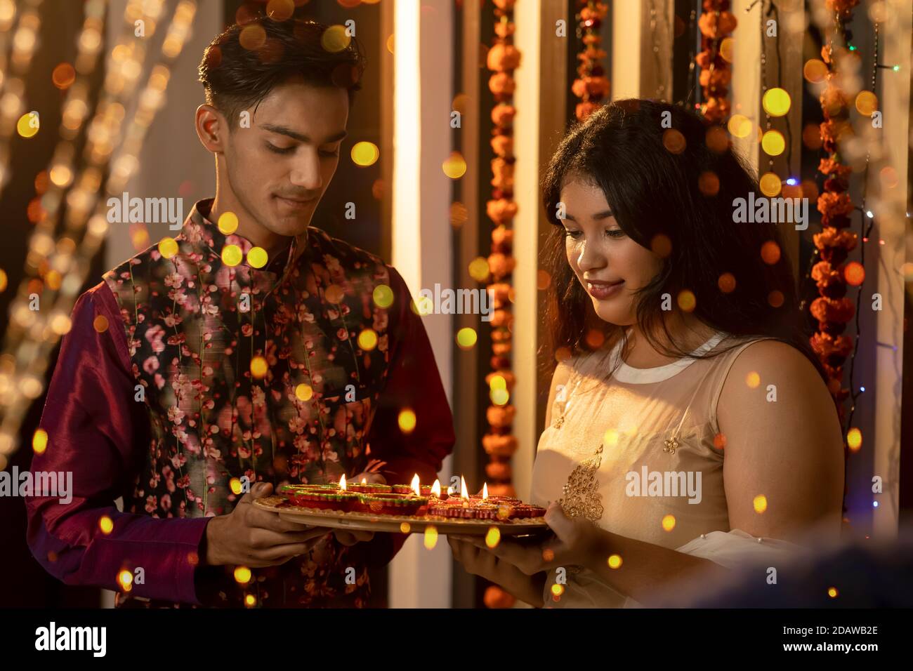 Ritratto di un uomo e di una donna indiani che illuminano diya e lampade in occasione delle feste di Diwali. Celebrazioni a casa. Foto Stock