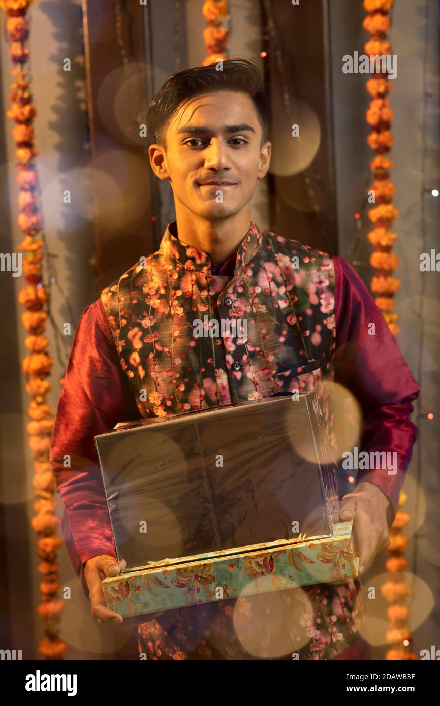 Ritratto di un indiano che tiene una scatola di regali in occasione di festa di Diwali. Celebrazioni a casa. Foto Stock