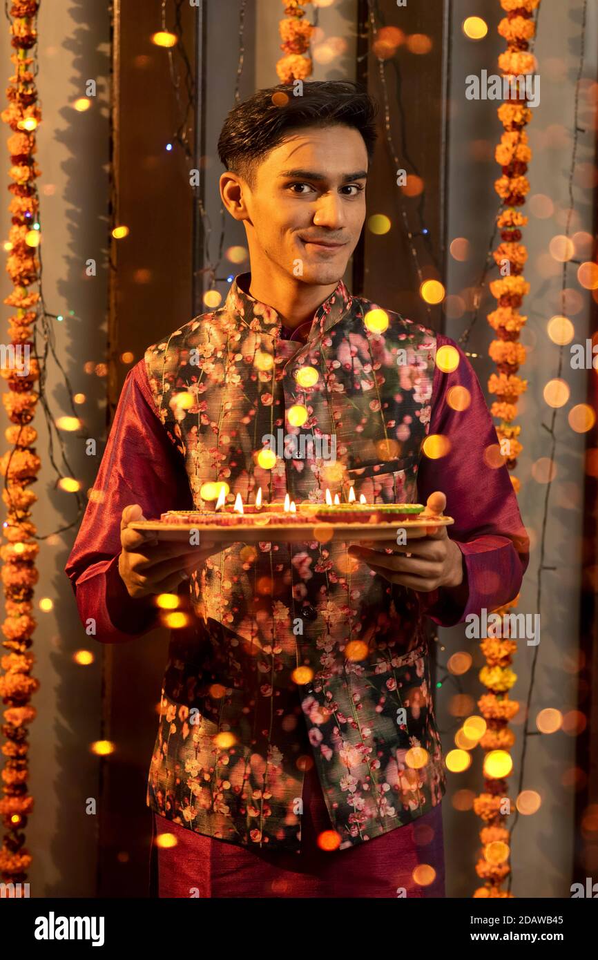 Ritratto di un indiano che tiene diya e lampade in occasione delle feste di Diwali. Celebrazioni a casa Foto Stock
