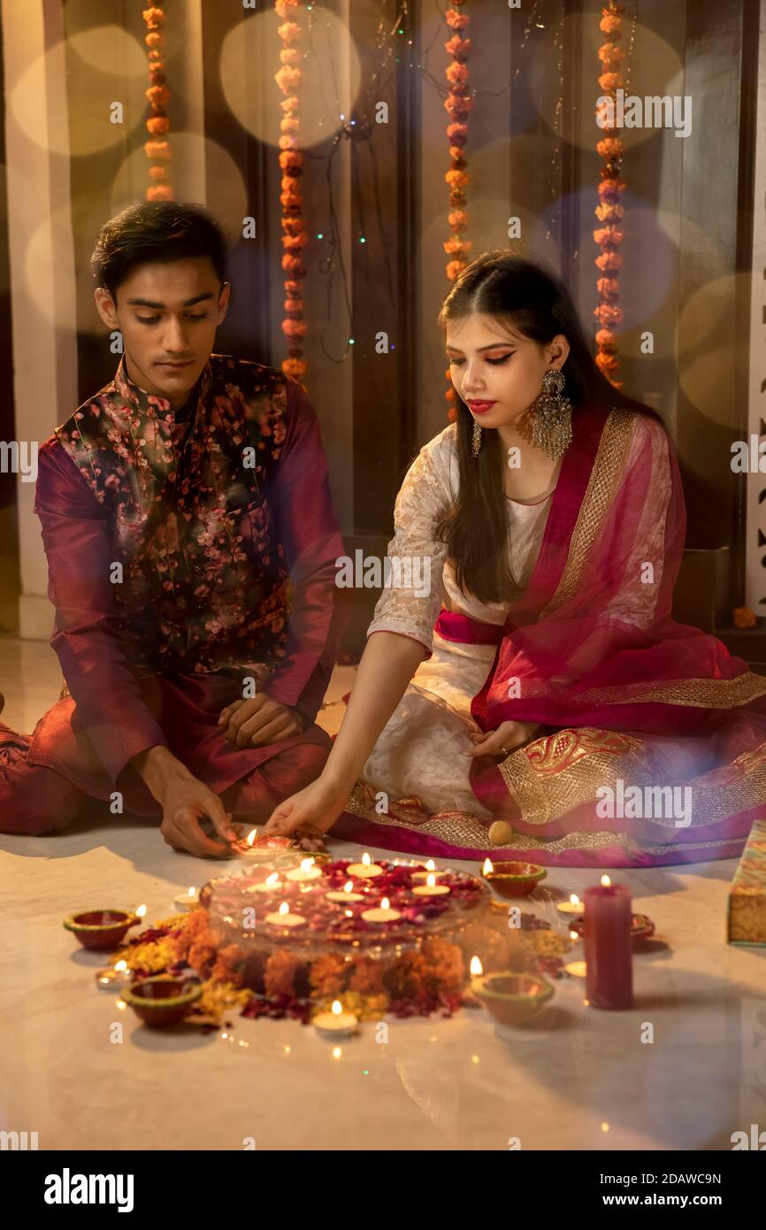Ritratto di un uomo e di una donna indiani che illuminano diya e lampade in occasione delle feste di Diwali. Celebrazioni a casa. Foto Stock