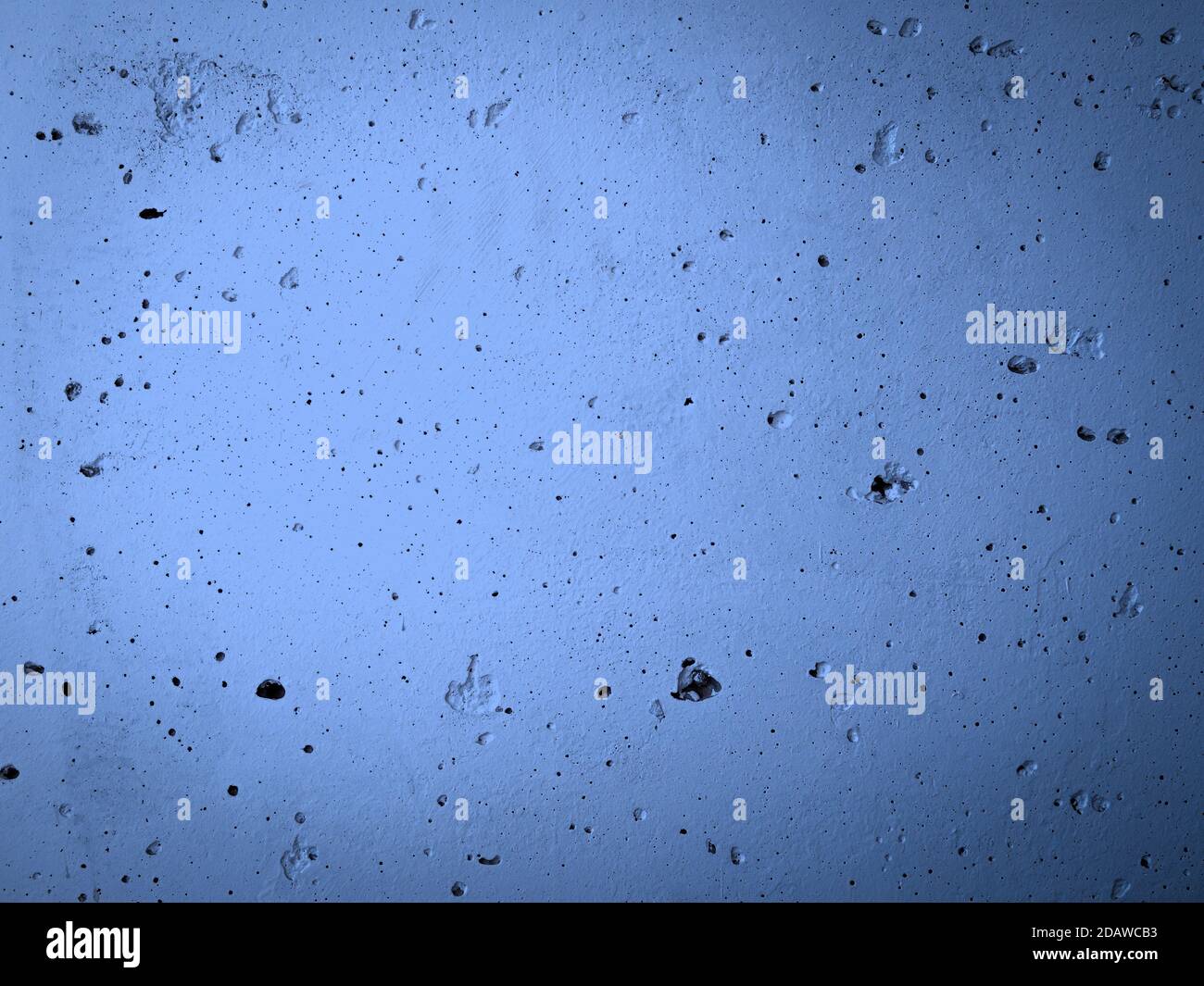 Parete in calcestruzzo con irregolarità verniciata con vernice blu. Sfondo astratto della superficie dell'edificio. Foto Stock