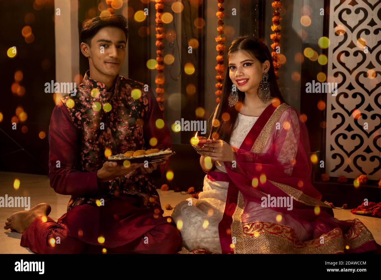 Ritratto di un uomo e di una donna indiani che illuminano diya e lampade in occasione delle feste di Diwali. Celebrazioni a casa. Foto Stock