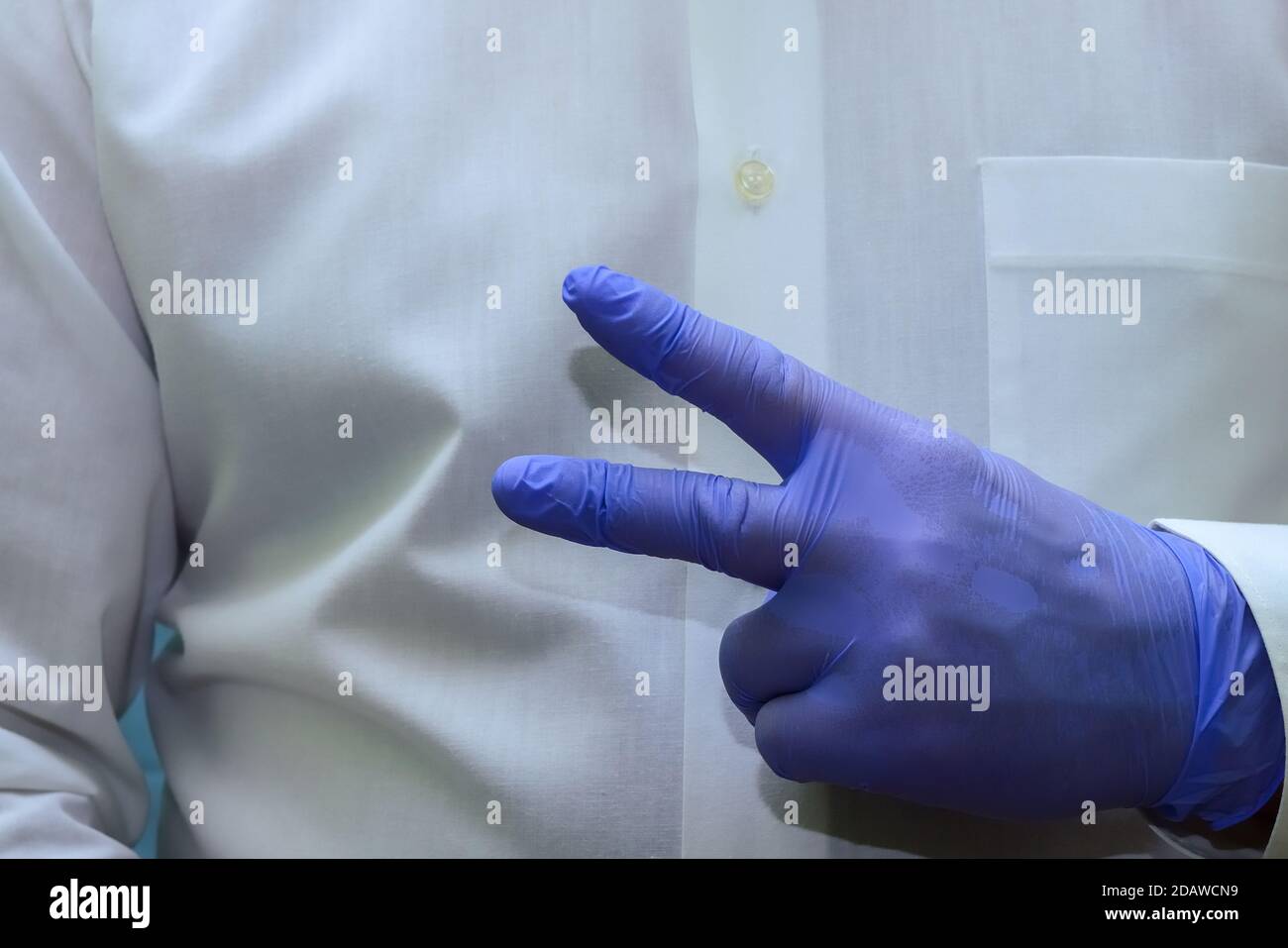 un uomo mostra due dita, forcelle - un gesto rude della mano in guanti di gomma medica monouso blu Foto Stock