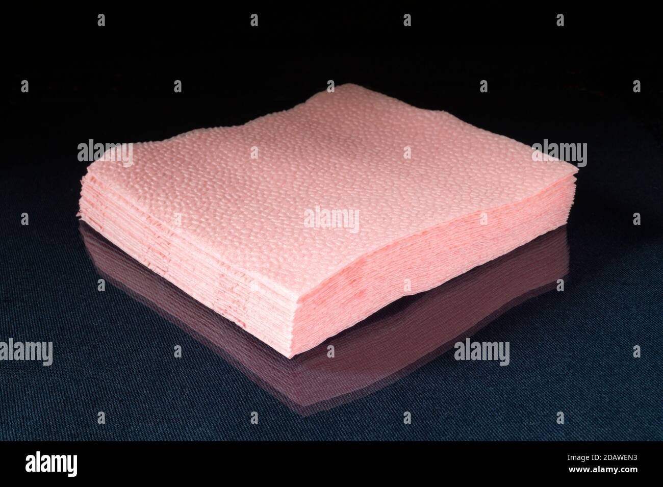 I tovaglioli di carta rosa su sfondo nero. Asciugamano Hygenic su tavola di vetro con riflesso Foto Stock