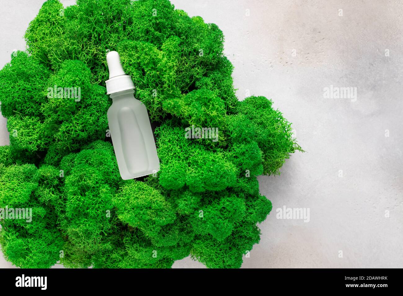 Siero anti-invecchiamento in bottiglia opaca su muschio verde. Foto Stock