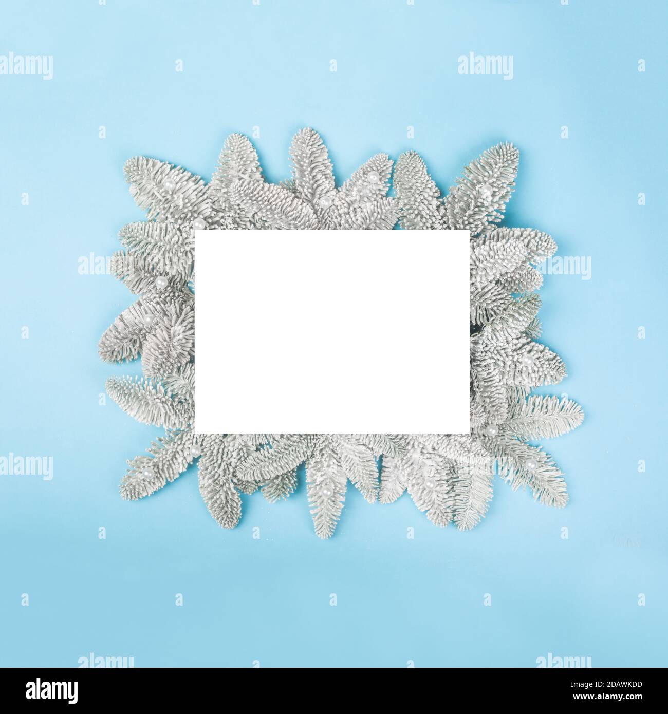 Rametti di abete smerigliati e fiocchi di neve decorativi natalizi su blu sfondo con cartoncino bianco con spazio di copia per il modello di testo vista dall'alto piatta desi Foto Stock