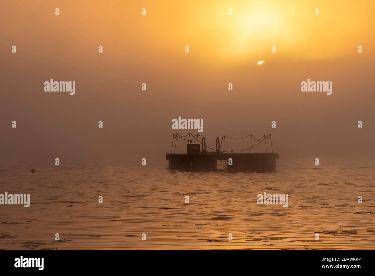 Prairieville, Michigan - UNA zattera galleggiante sul lago Stewart mentre il sole raggiunge la nebbia mattutina. Foto Stock